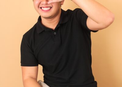 The Young Juanderer in a black shirt and khaki pants smiling and gesturing with hand.