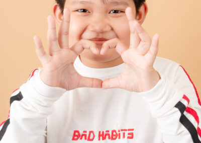 A boy forming a heart shape with his hands, known as a "finger heart"